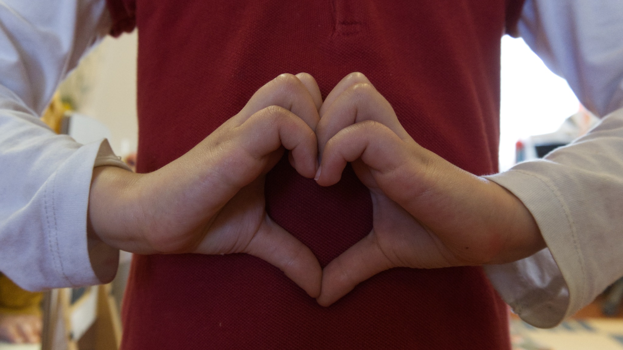 Kädet muodostavat sydämen punaiselle paidalle, kuva